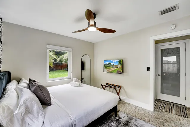 a large bed sitting in a bedroom next to a window and a potted plant