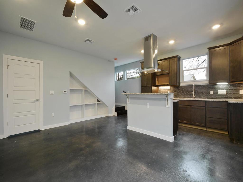 1608 Miriam Avenue, Unit B Austin, TX 78702 - Photo 1 of 10 Kitchen with island range hood, dark brown cabinetry, concrete flooring, light stone countertops, and recessed lighting