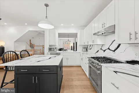 a kitchen with stainless steel appliances a sink dishwasher stove and white cabinets with wooden floor