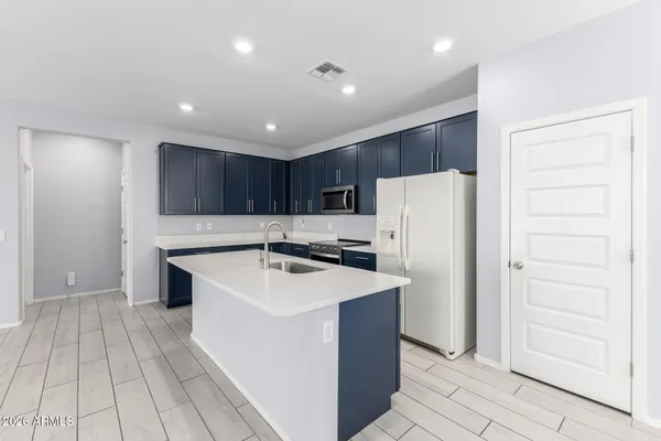a kitchen with a sink a refrigerator and a stove top oven with wooden floor