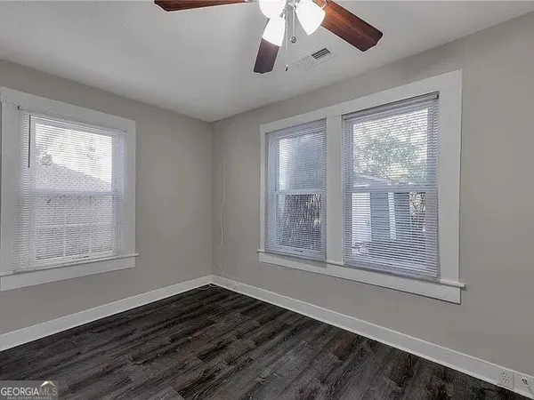 a view of an empty room with wooden floor and a window