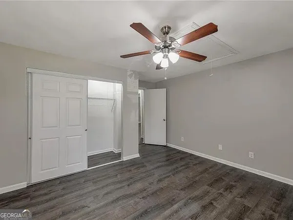 an empty room with wooden floor fan and windows