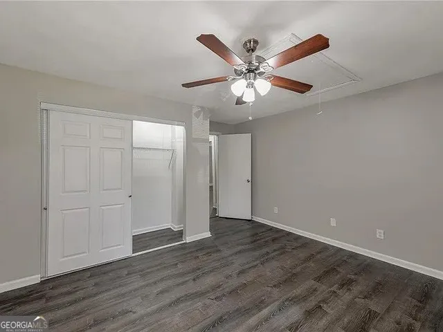 an empty room with wooden floor fan and windows