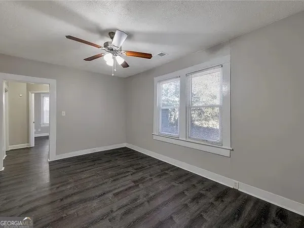 a view of an empty room with wooden floor and a window
