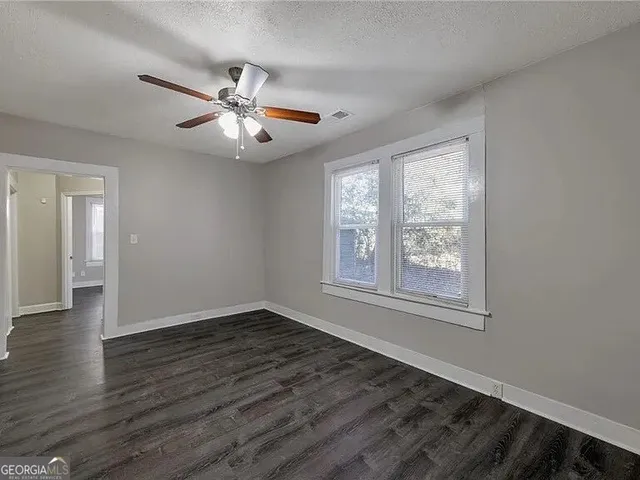 a view of an empty room with wooden floor and a window