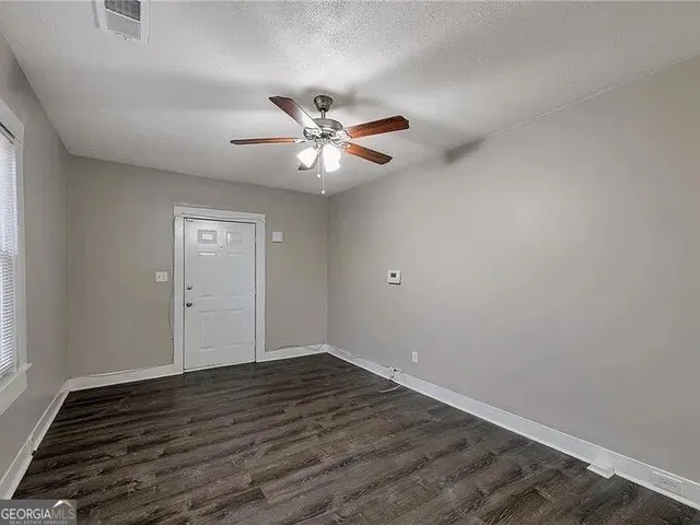 an empty room with wooden floor and ceiling fan