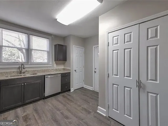 a view of a kitchen with granite countertop a sink and dishwasher with wooden floor