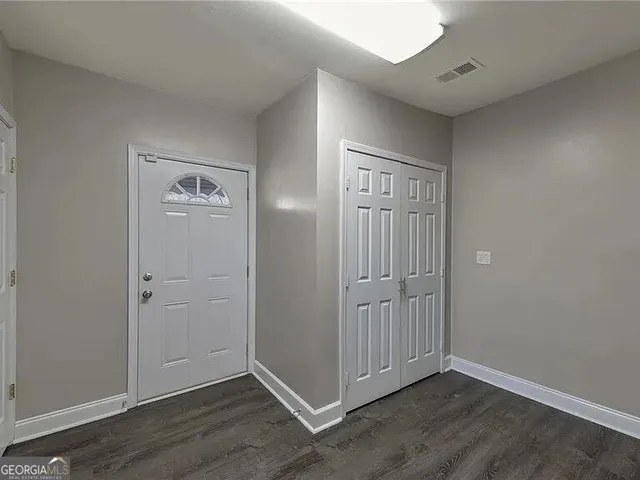 an empty room with wooden floor & closet area