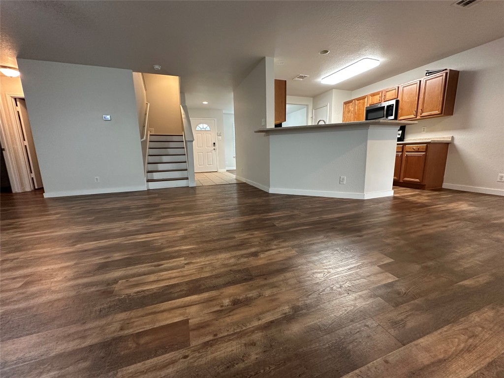113 Lex Word Kyle, TX 78640 - Photo 19 of 40 an empty room with wooden floor and a kitchen