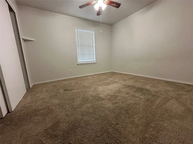an empty room with wooden floor and a kitchen