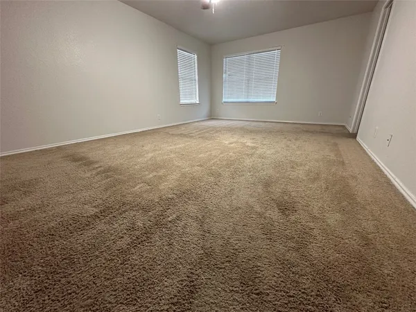 en empty room with windows and ceiling fan