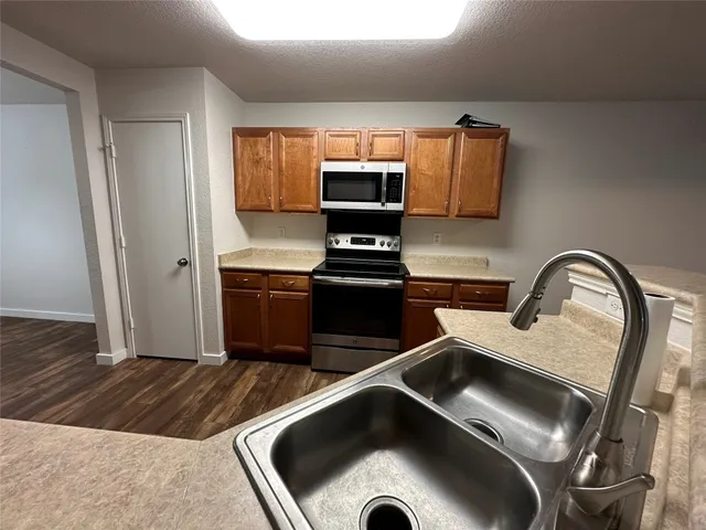 a living room with stainless steel appliances furniture a fireplace a flat screen tv and view kitchen