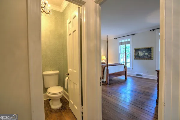 an empty room with wooden floor chandelier and windows