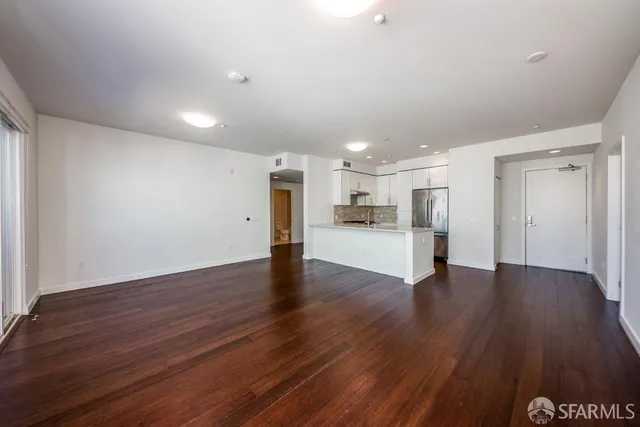 a view of a kitchen with a fridge and wooden floor