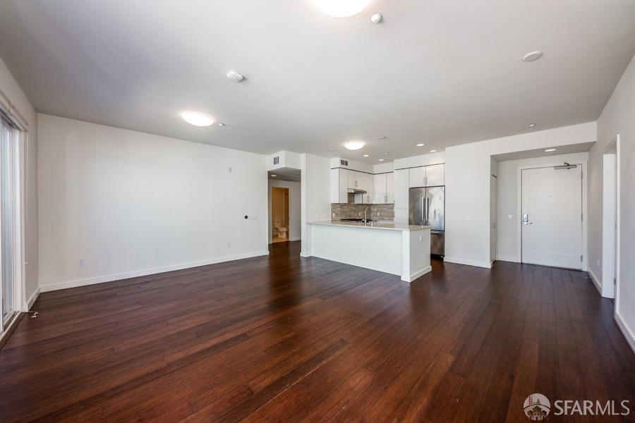 a view of a kitchen with a fridge and wooden floor