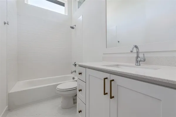 a bathroom with a granite countertop sink a toilet and shower
