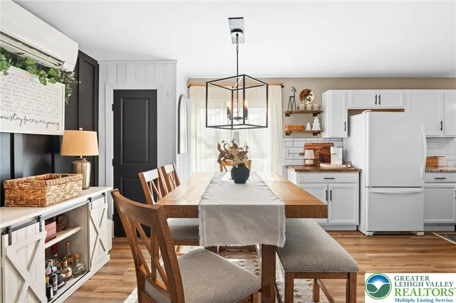 a kitchen with a refrigerator a stove a sink dishwasher and a dining table with wooden floor