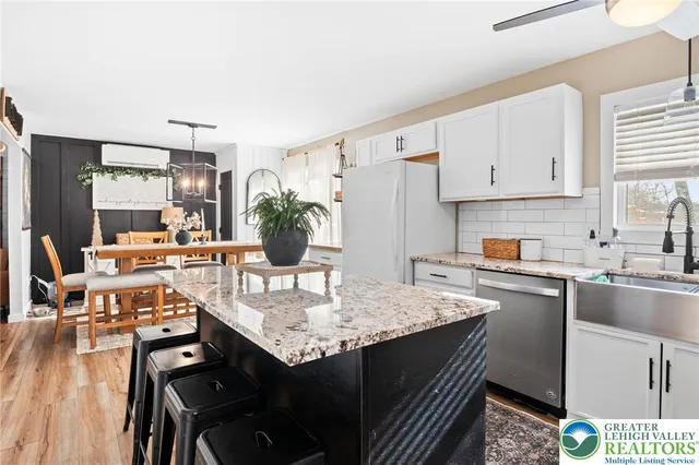 a kitchen with a sink dishwasher a stove a dining table and chairs with wooden floor