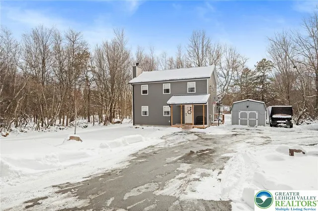 a front view of a house with a yard covered in snow
