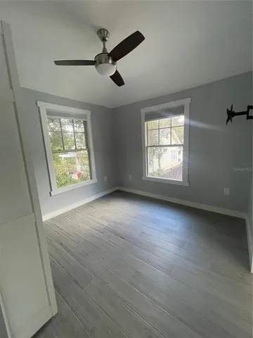 a view of an empty room with a window and wooden floor
