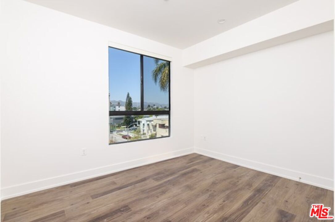 129 South Kings Road, Unit PH5 Los Angeles, CA 90048 - Photo 11 of 14 a view of an empty room with wooden floor and a window