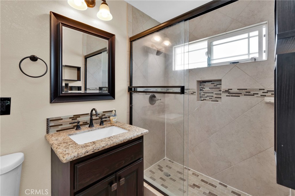 a bathroom with a granite countertop sink mirror vanity and toilet