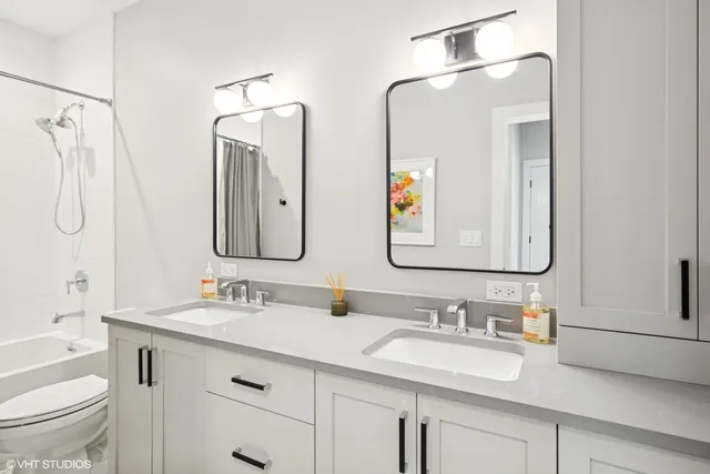 a bathroom with double vanity sinks a toilet a mirror and shower