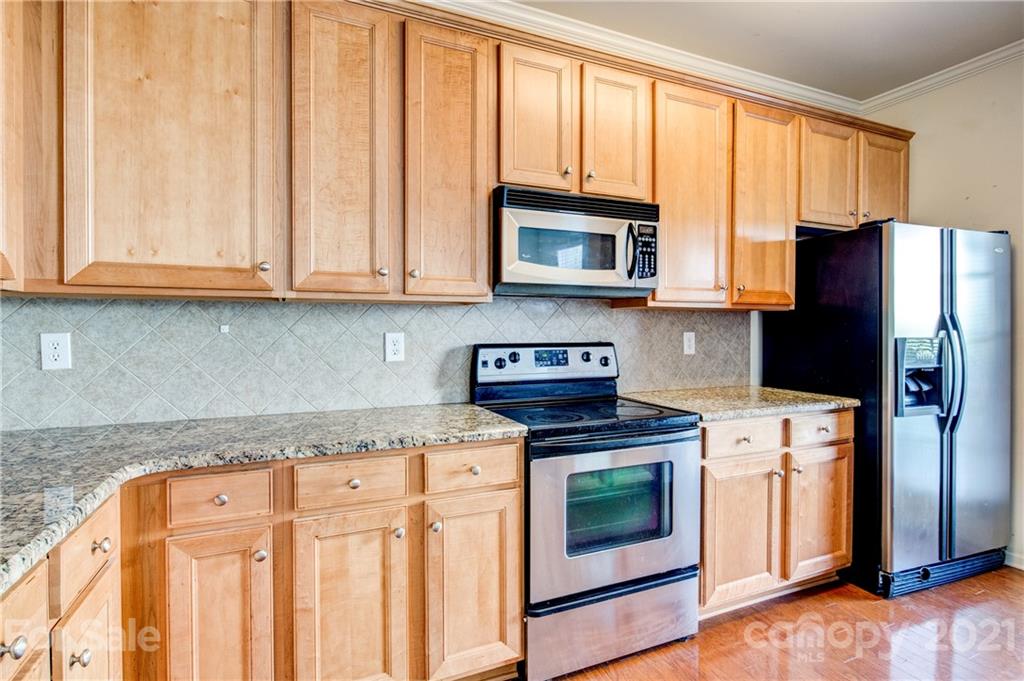 1310 Smokey Quartz Lane Fort Mill, SC 29708 - Photo 6 of 18 a kitchen with granite countertop a stove top oven microwave and refrigerator