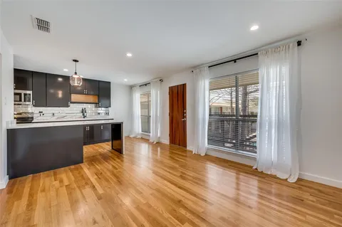 a kitchen with stainless steel appliances kitchen island granite countertop a refrigerator a stove a sink dishwasher and white cabinets with wooden floor