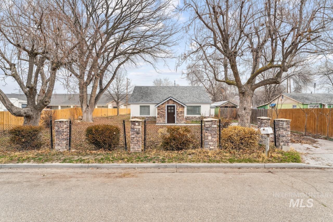 View of front facade featuring a fenced front yard, stone siding, and a gate