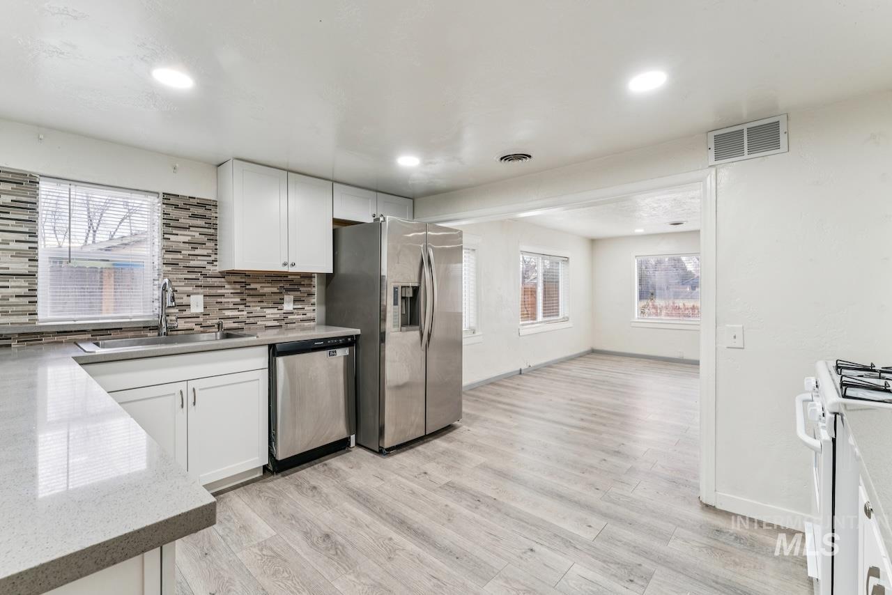 317 East Ithaca Street Caldwell, ID 83605 - Photo 11 of 49 Kitchen with white cabinetry, light wood-type flooring, decorative backsplash, stainless steel appliances, and light stone countertops