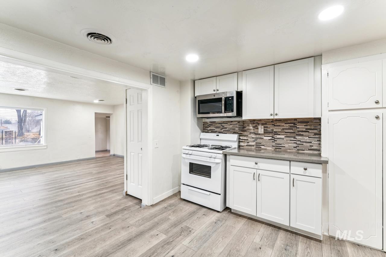 317 East Ithaca Street Caldwell, ID 83605 - Photo 12 of 49 Kitchen with white range with gas stovetop, white cabinets, stainless steel microwave, and light wood finished floors