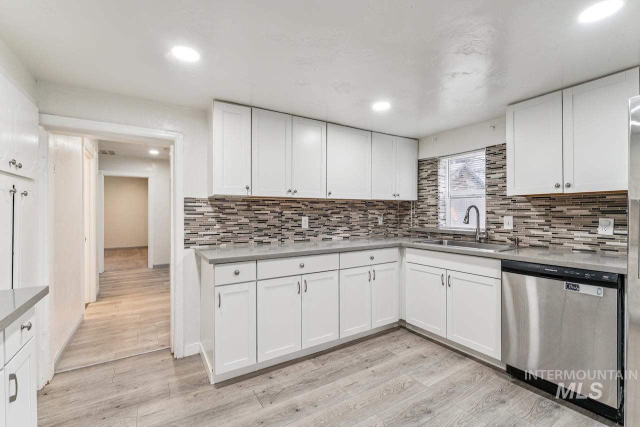 317 East Ithaca Street Caldwell, ID 83605 - Photo 13 of 49 Kitchen featuring dishwasher, white cabinetry, tasteful backsplash, light wood finished floors, and light stone countertops