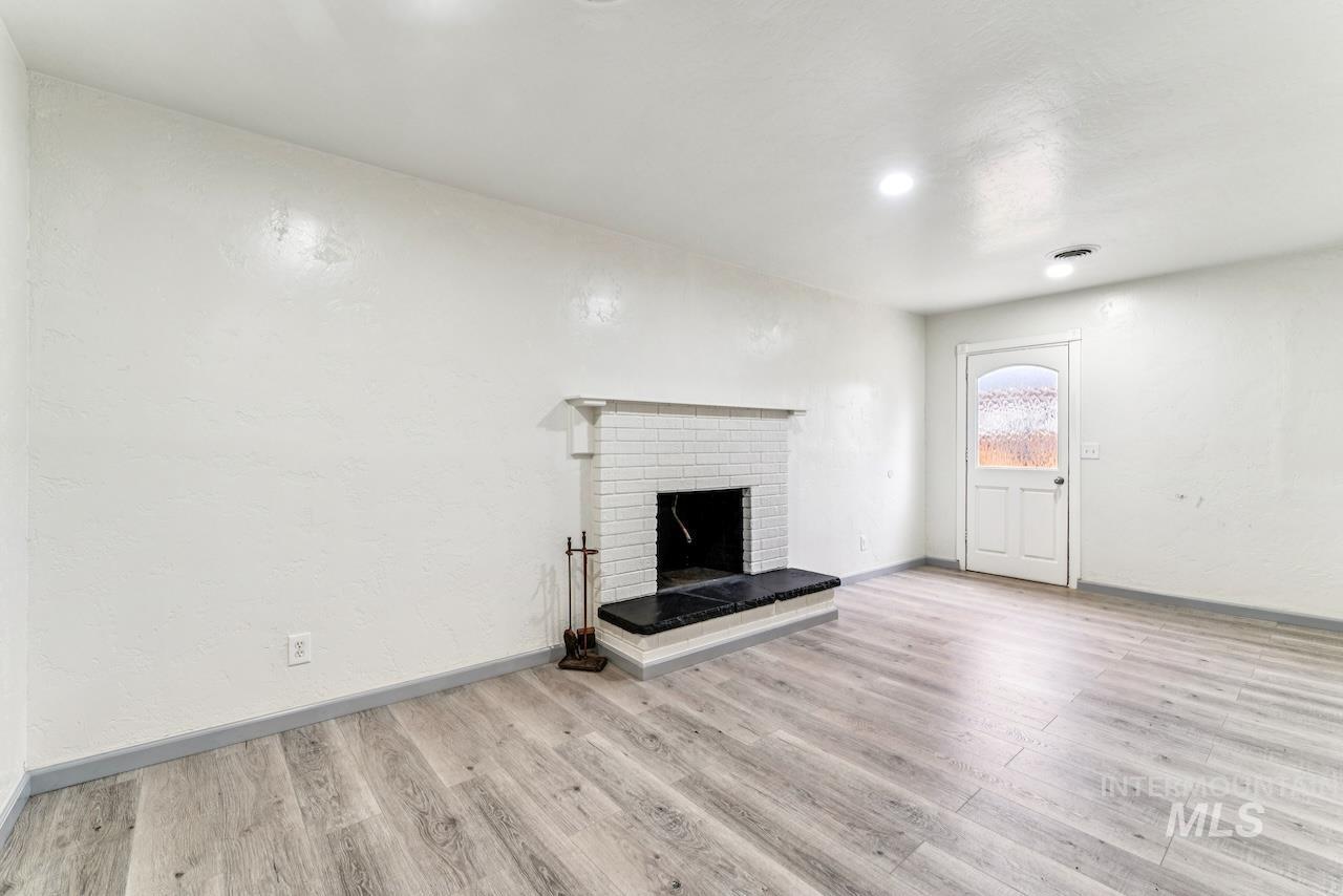 317 East Ithaca Street Caldwell, ID 83605 - Photo 17 of 49 Unfurnished living room featuring a brick fireplace and light wood finished floors