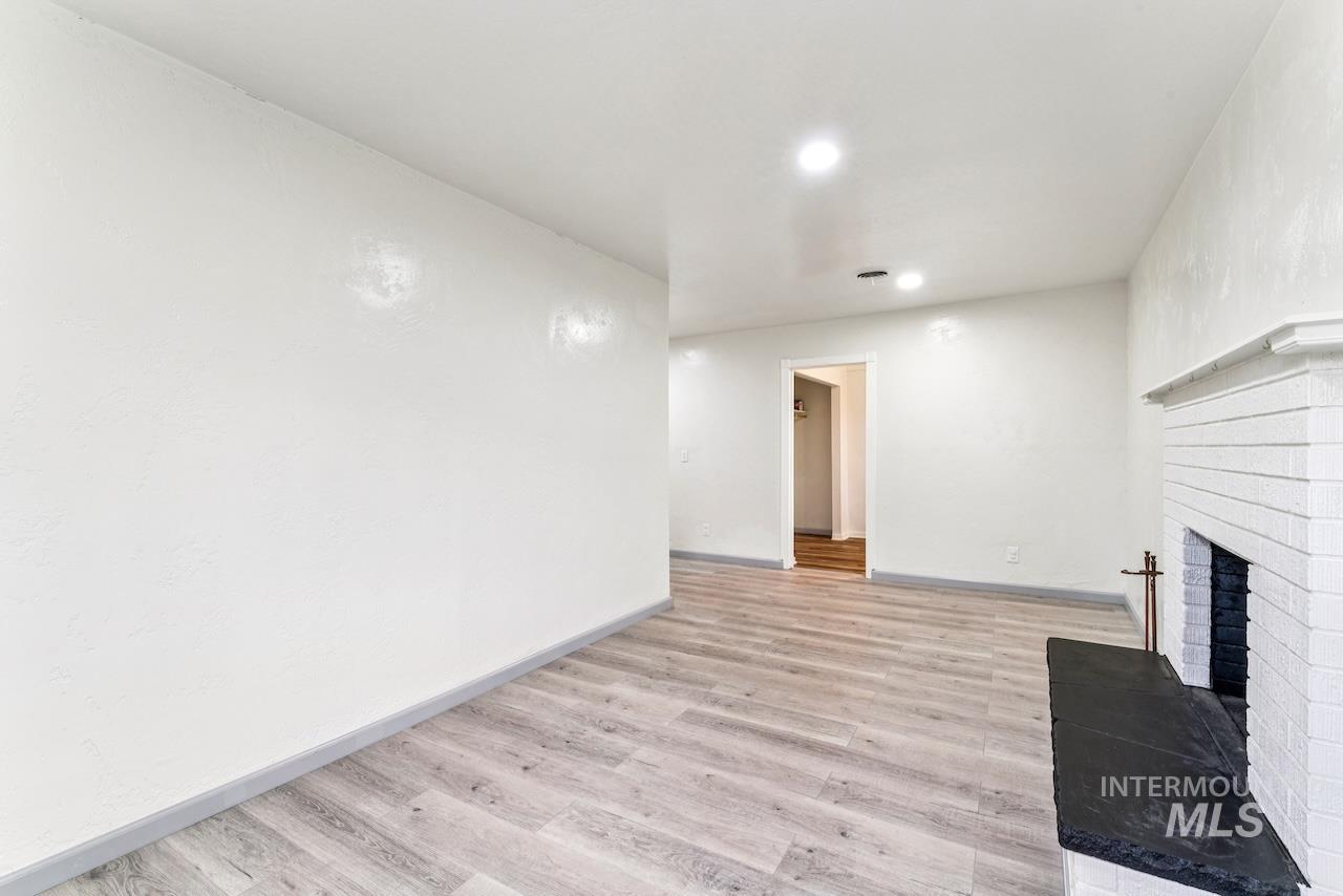 317 East Ithaca Street Caldwell, ID 83605 - Photo 18 of 49 Unfurnished living room with light wood-style flooring, a brick fireplace, and recessed lighting