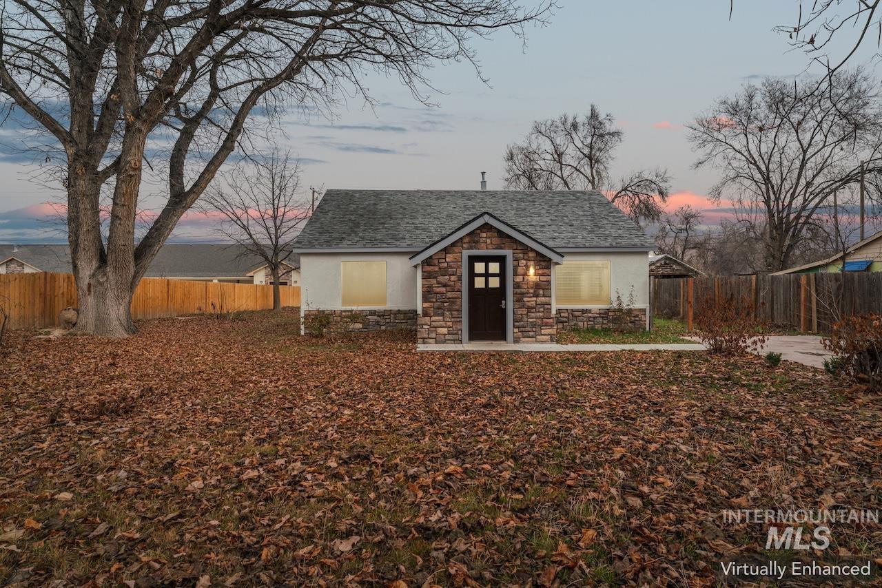 317 East Ithaca Street Caldwell, ID 83605 - Photo 2 of 49 View of front of property featuring a fenced backyard, stone siding, roof with shingles, and an outbuilding