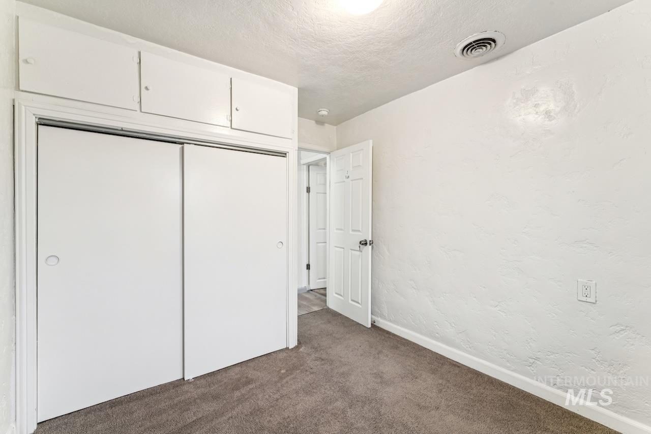 317 East Ithaca Street Caldwell, ID 83605 - Photo 40 of 49 Unfurnished bedroom featuring a textured wall, a closet, a textured ceiling, and dark colored carpet