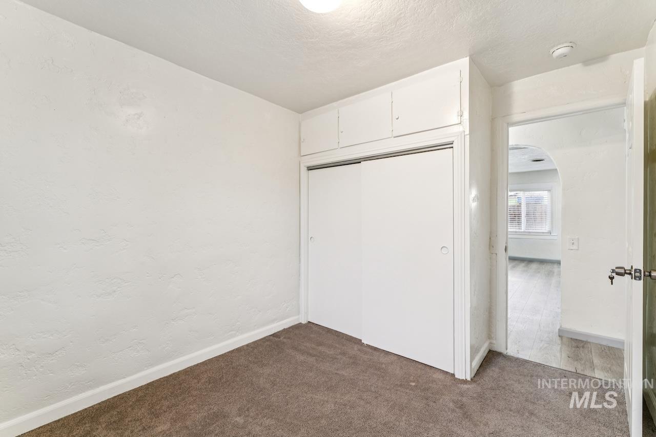 317 East Ithaca Street Caldwell, ID 83605 - Photo 41 of 49 Unfurnished bedroom featuring arched walkways, a closet, a textured ceiling, dark carpet, and a textured wall
