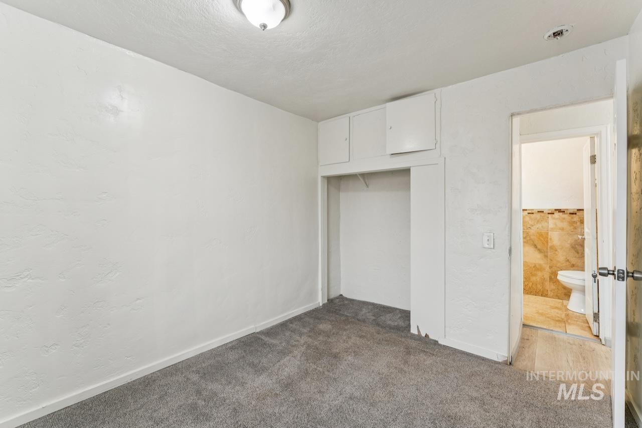317 East Ithaca Street Caldwell, ID 83605 - Photo 44 of 49 Unfurnished bedroom featuring a textured wall, dark carpet, a closet, and a textured ceiling