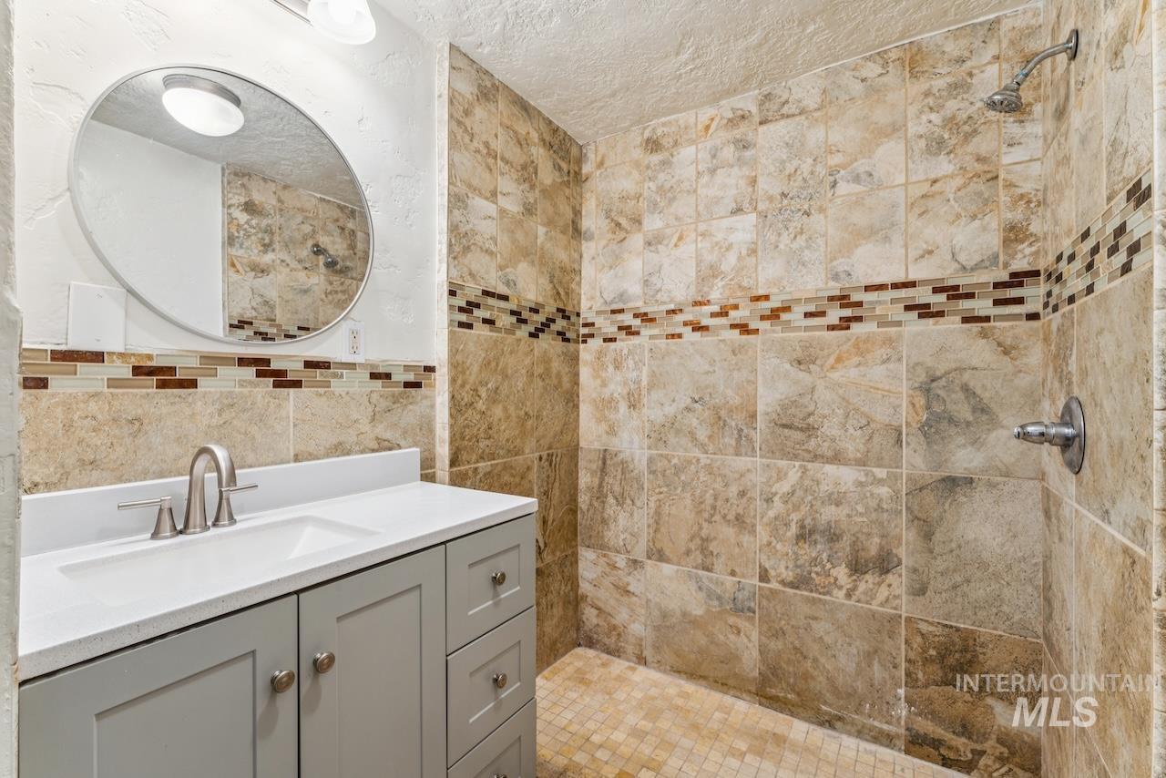 317 East Ithaca Street Caldwell, ID 83605 - Photo 45 of 49 Bathroom featuring vanity, tiled shower, a textured ceiling, and tile walls