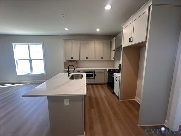 a kitchen with stainless steel appliances granite countertop a refrigerator a sink dishwasher a stove and white countertops with wooden floor