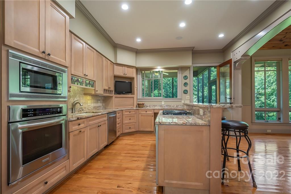 1360 South Phillips Road Columbus, NC 28722 - Photo 15 of 41 a kitchen with kitchen island granite countertop a stove top oven a sink a dining table and chairs with wooden floor