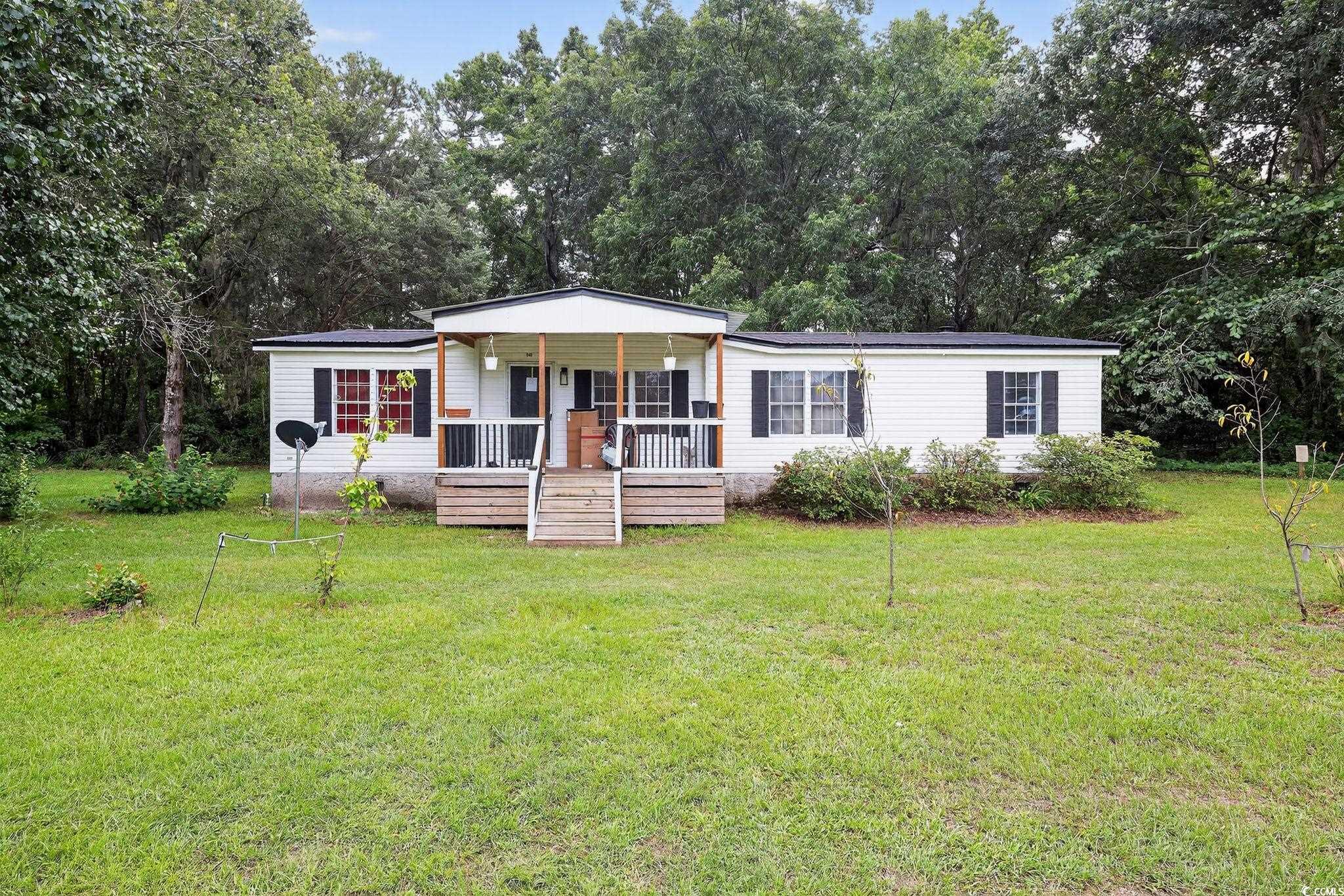 View of front facade featuring covered porch, a metal roof, and a front lawn