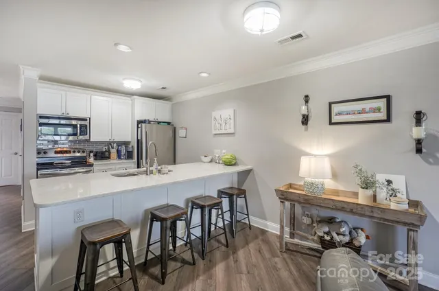 a view of center island with kitchen island a sink wooden floor and living room view