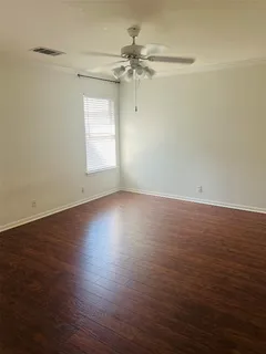 an empty room with wooden floor fan and windows