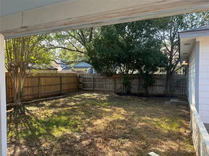 a backyard of a house with a large tree and plants
