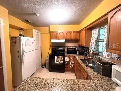a living room with stainless steel appliances granite countertop furniture and a refrigerator