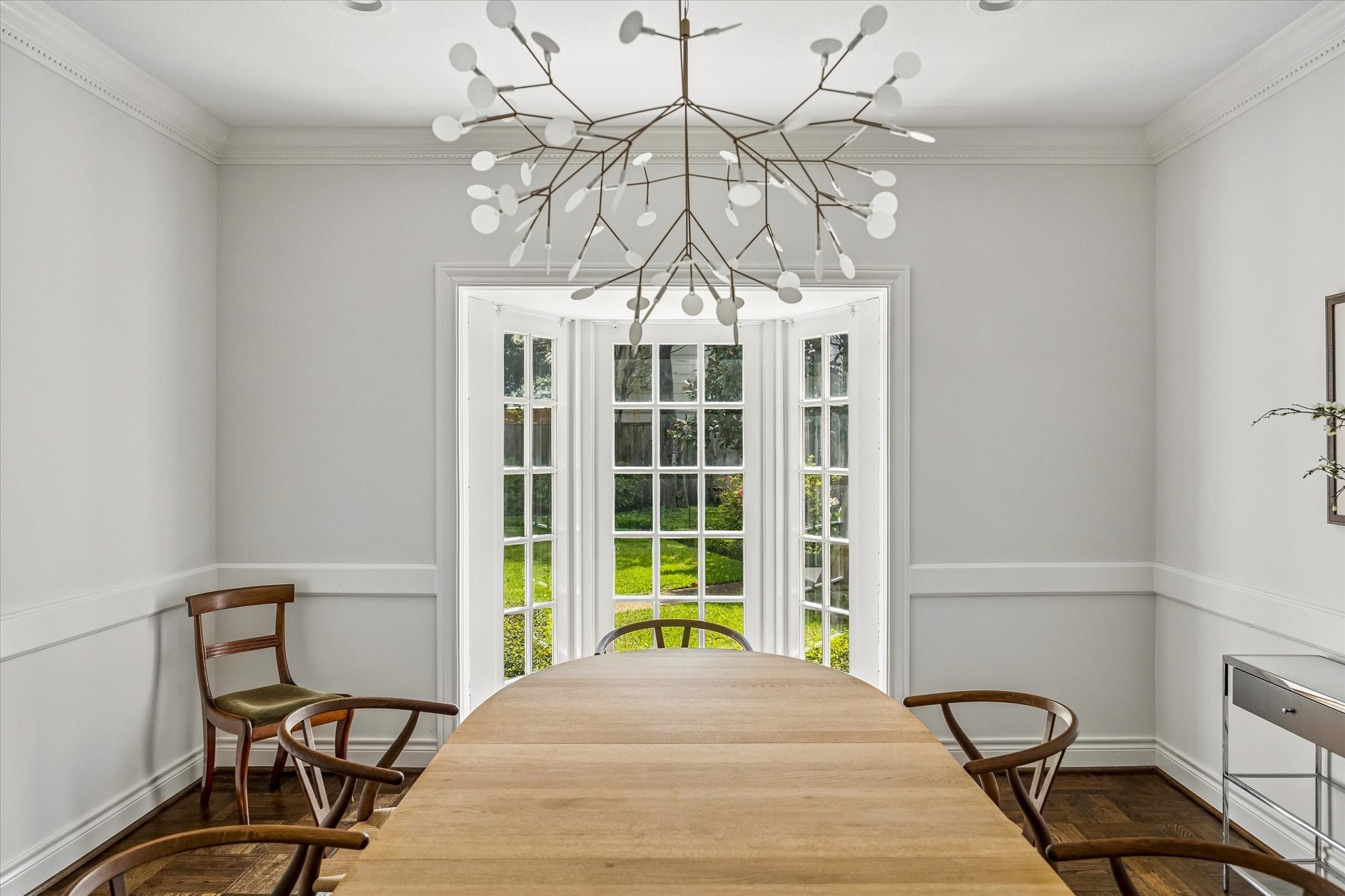 2133 Inwood Drive Houston, TX 77019 - Photo 12 of 22 A statement chandelier crowns the dining space, with tall windows framing serene garden views.