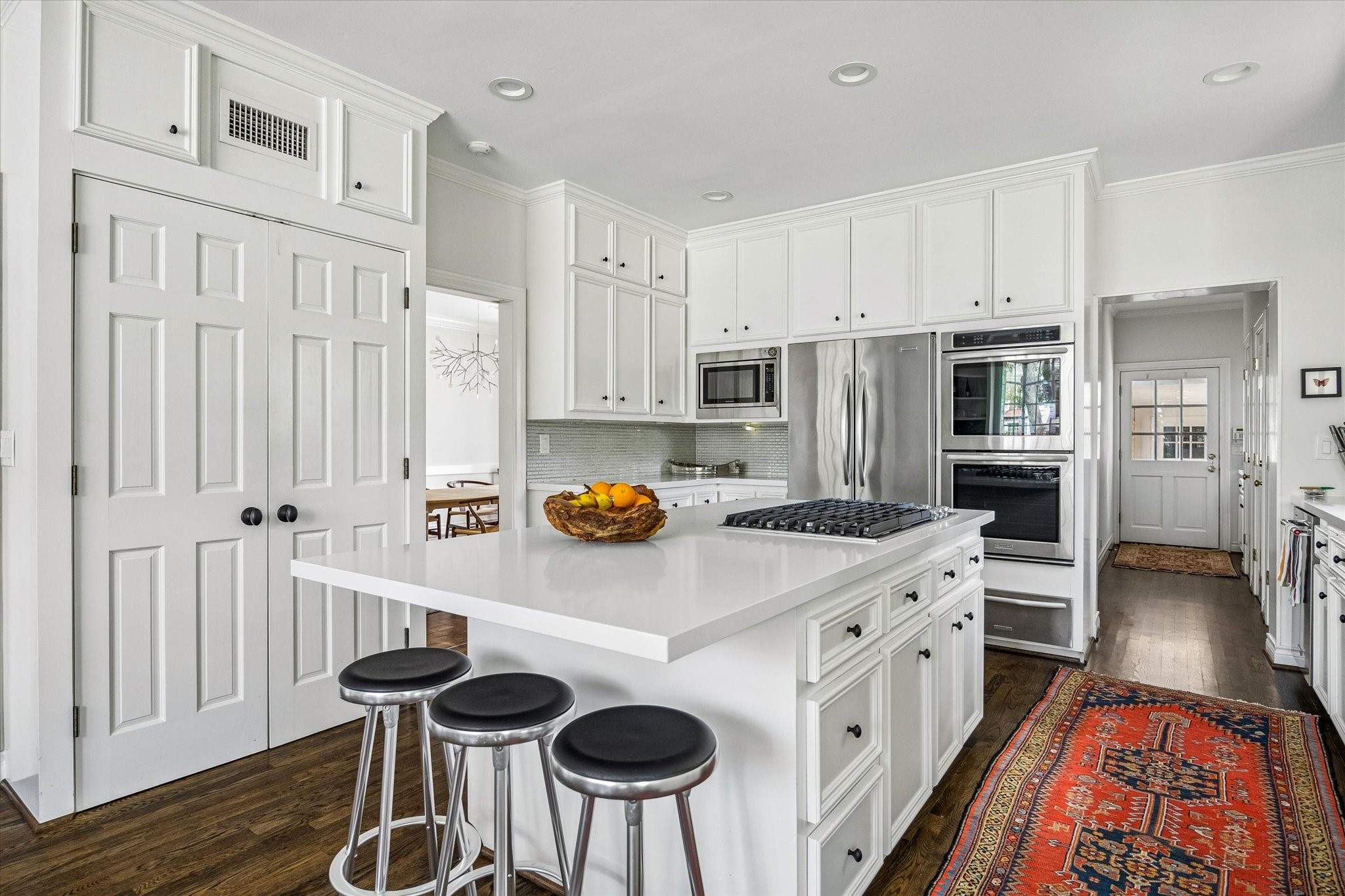 2133 Inwood Drive Houston, TX 77019 - Photo 13 of 22 A crisp, all-white kitchen anchored by a central island, blending classic cabinetry with modern function.