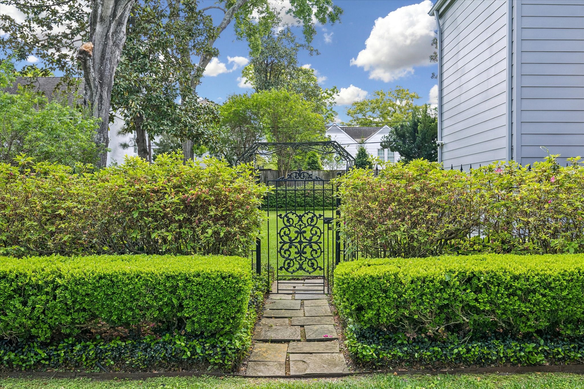 2133 Inwood Drive Houston, TX 77019 - Photo 18 of 22 A storybook garden entry framed by manicured hedges and a decorative iron gate.